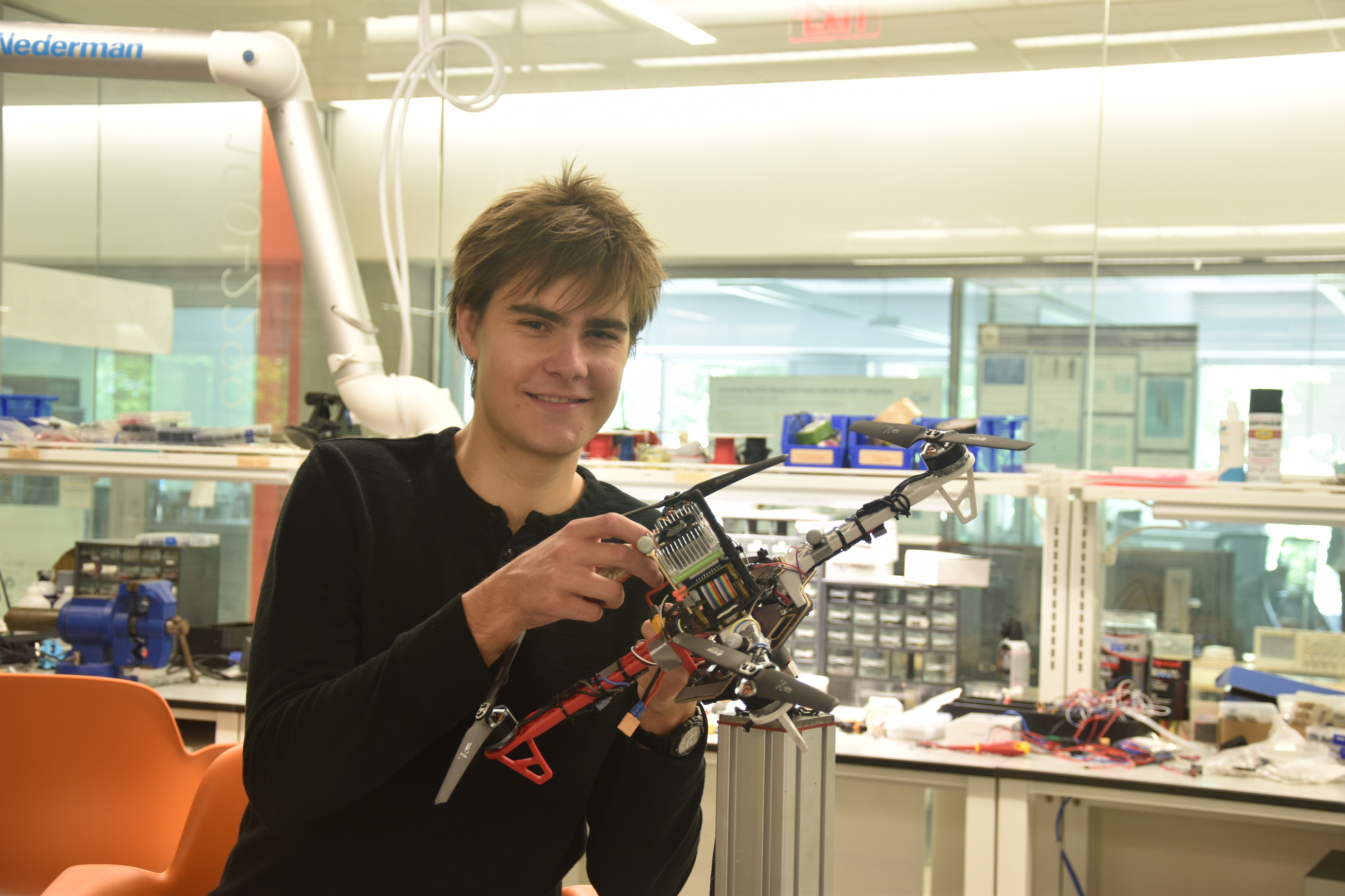 Karl Simon holding a drone in the flight test facility of the Science & Engineering Hall