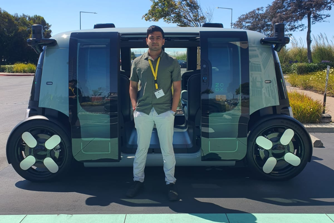 Shrey Patel in front of Zoox's autonomous vehicle.