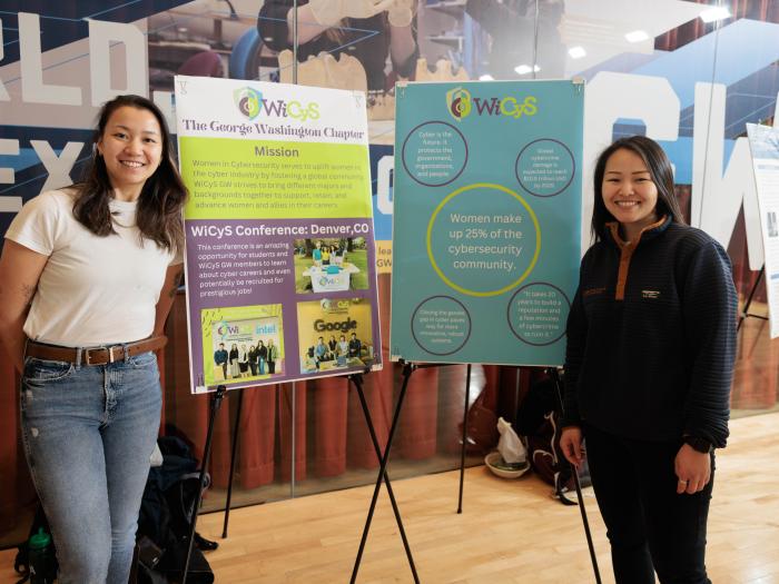 Lena Rose and Darika Shaibekova standing in front of WiCys posters