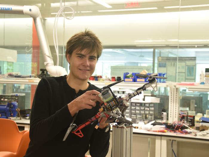 Karl Simon holding a drone in the flight test facility of the Science & Engineering Hall
