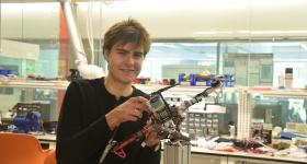 Karl Simon holding a drone in the flight test facility of the Science & Engineering Hall
