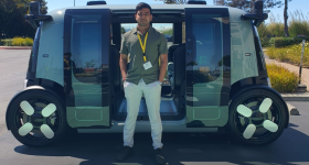 Shrey Patel in front of Zoox's autonomous vehicle.